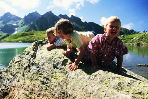 three children playing on a rock near a body of water at Serviced Apartments Wallis in Mörel
