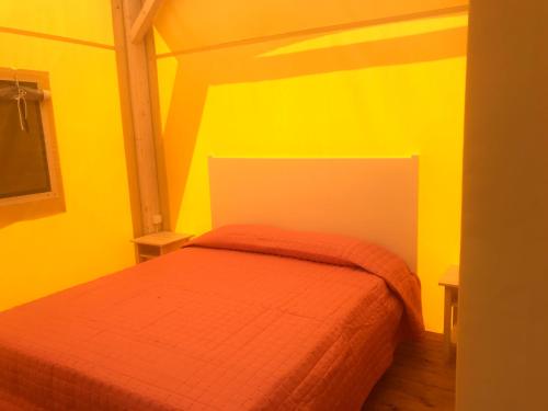 a bedroom with a bed with yellow walls at Vento etrusco in Riotorto