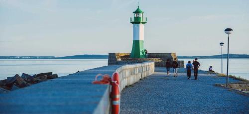a lighthouse on a beach with people walking on it at Villa am Kreidebruch _ Komfort_App in Sassnitz
