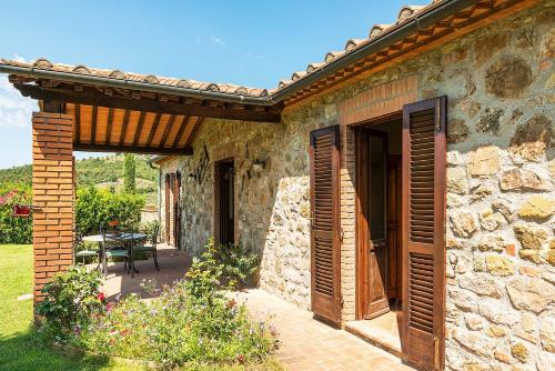 a stone house with an open door and a patio at Agriturismo Pian del Vescovo in Massa Marittima