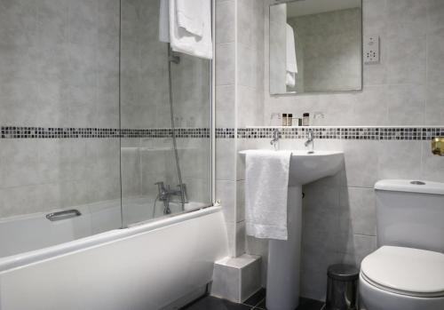 een badkamer met een bad, een toilet en een wastafel bij The Lion Hotel in Belper