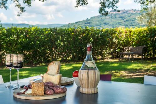a table with a bottle of wine and some cheese at Agriturismo Pian del Vescovo in Massa Marittima