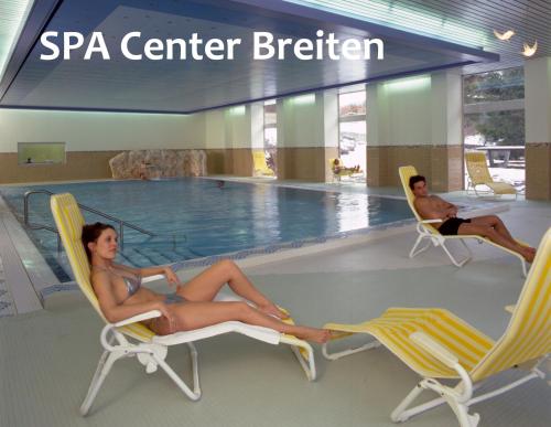 two women sitting in chairs in front of a swimming pool at Serviced Apartments Wallis in Mörel