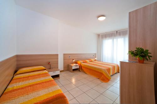a hotel room with two beds and a window at Residence Roberta in Caorle