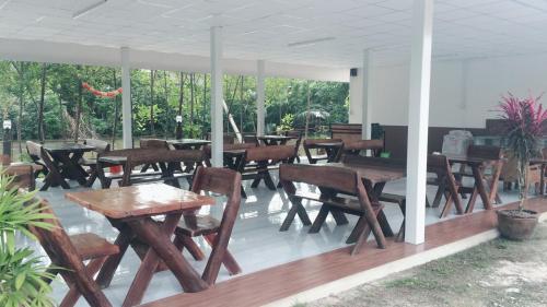 a group of wooden tables and chairs on a patio at Saeng Tai Amphawa in Samut Songkhram