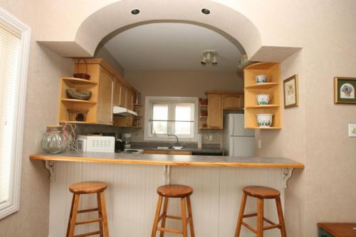 a kitchen with a counter with three bar stools at Highlands Four Season Resort in Calabogie