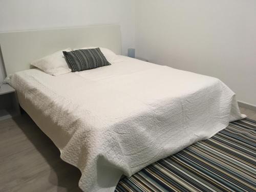 a white bed with a blanket on top of it at Santa Cruz Flat - Alojamento Local in Praia da Vitória