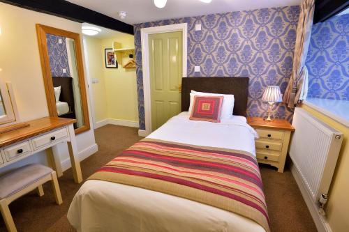 a small bedroom with a bed and a mirror at The Green Dragon in Wellington