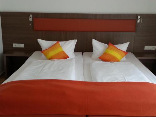 a bedroom with two beds with colorful pillows at Hotel Aviva in Karlsruhe