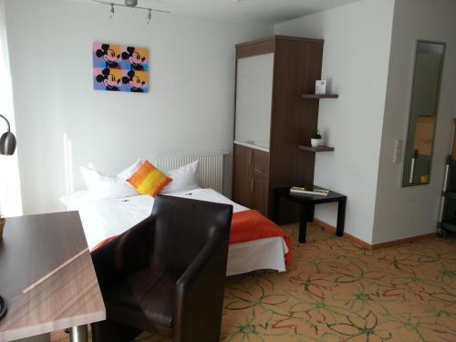 a bedroom with a bed and a desk and a chair at Hotel Aviva in Karlsruhe