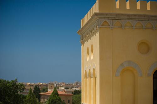 a building with a tower with a city in the background at Villa le Torri B&B in Trapani