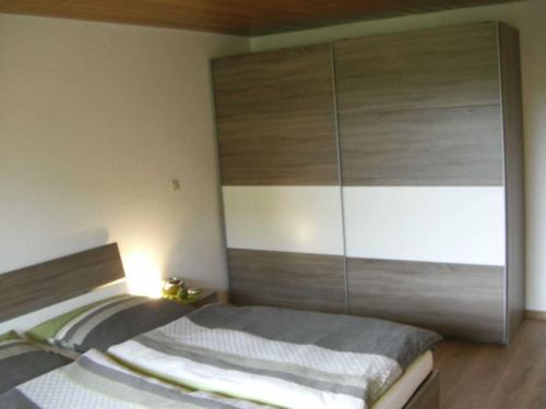 1 dormitorio con 1 cama y un gran armario de madera en Apartment Heilbrünnchen, en Emmelshausen