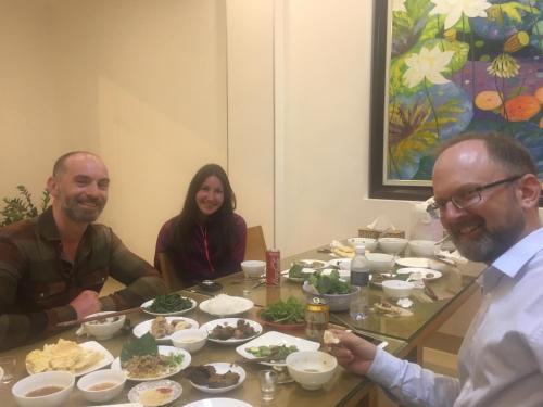 a group of people sitting around a table with food at The Melbourne Hotel in Ninh Binh