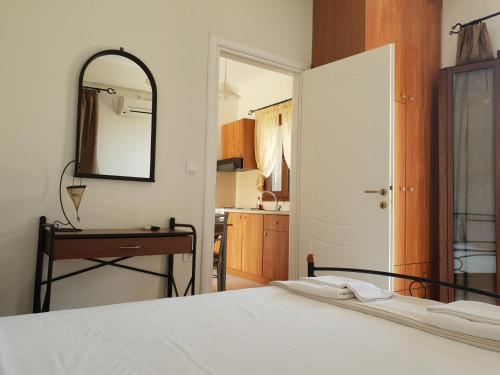 a bedroom with a white bed and a mirror at Domaine Papakonstantis in Skoutari