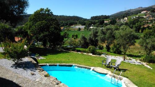 uma piscina com duas espreguiçadeiras ao lado em Quinta do Riacho em Póvoa de Lanhoso