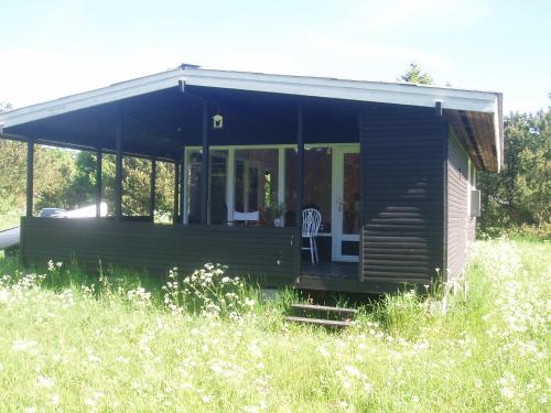 a wooden cabin in a field of tall grass at Summer cottage in Nøreng