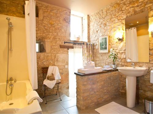 baño de piedra con lavabo, bañera y aseo en La Chartreuse du Maine, en Cubjac