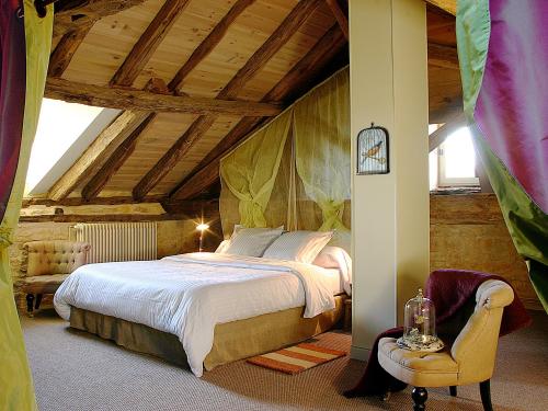Un dormitorio con una cama grande y una silla. en La Chartreuse du Maine, en Cubjac