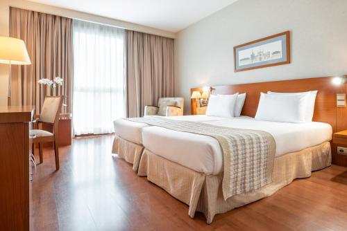 a hotel room with a large bed and a desk at Eurostars San Lazaro in Santiago de Compostela