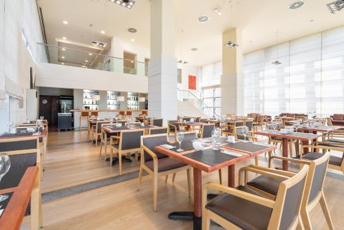 a dining room with wooden tables and chairs at Eurostars San Lazaro in Santiago de Compostela