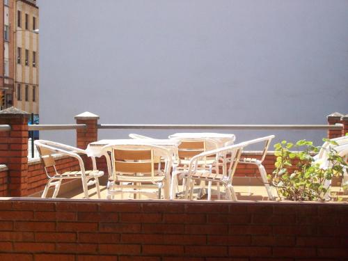 a group of white chairs and tables on a balcony at Pensión Los Pinos Gijón in Gijón