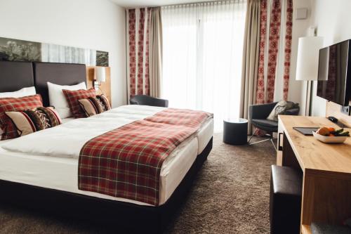 a hotel room with a large bed and a desk at Hotel Edita in Scheidegg