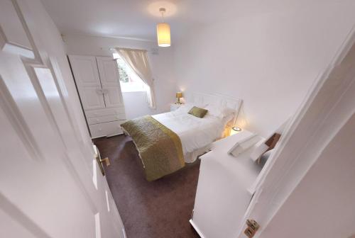 a small white bedroom with a bed and a window at Riverview Luxury Short Stay Apartment in Enniscorthy