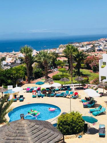 a resort with a pool and chairs and the ocean at Regency Torviscas Apartments and Suites in Adeje
