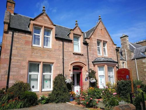una gran casa de ladrillo con puerta roja en St Ann’s Guest House, en Inverness