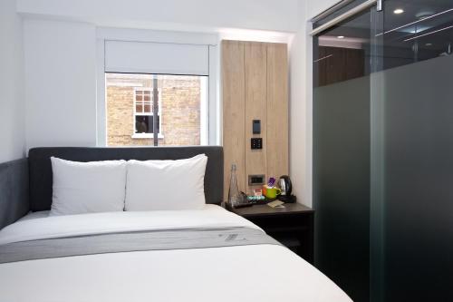 1 dormitorio con cama blanca y ventana en The Z Hotel Tottenham Court Road en Londres