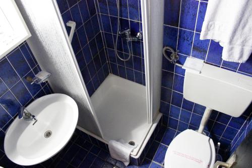a blue tiled bathroom with a toilet and a sink at Hotel Grand in Sarajevo