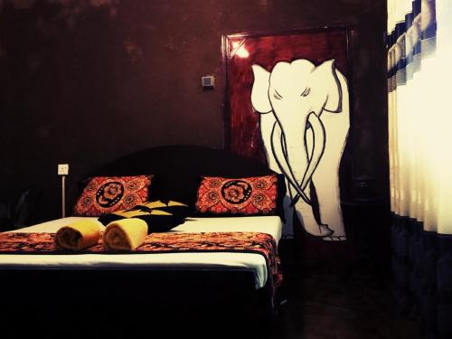 a bedroom with a bed with an elephant painted on the wall at Ancient Gardens - Villa in Pinnawala