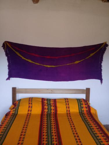 a blanket hanging on a wall above a bed at Cabaña El Cardón,casita en el campo quebradeño in Humahuaca
