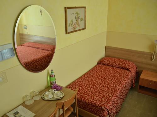 a small room with a bed and a mirror at Hotel Sorriso in Toscolano Maderno
