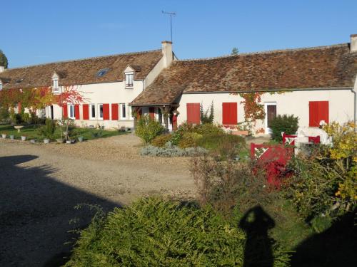 a white house with red shutters and a yard at Ferme les Rousseaux in La Belliole