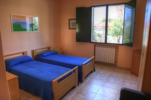sypialnia z 2 łóżkami i oknem w obiekcie La casa tra i limoni w mieście SantʼAgata di Militello