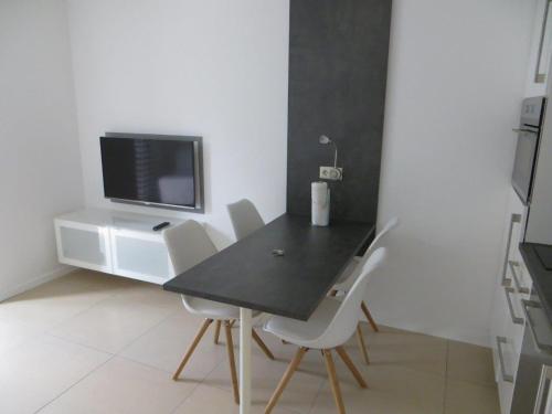 a dining room with a black table and white chairs at Ferienwohnung BELVEDERE in Rust