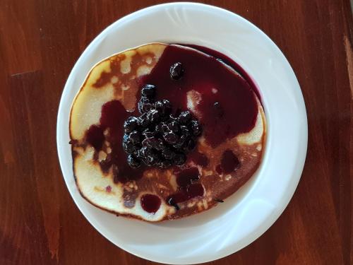 a plate of pancakes with syrup and berries on it at Fresh Accommodation in Rădăuţi