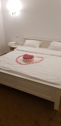 a white bed with a bowl of roses on it at Fresh Accommodation in Rădăuţi