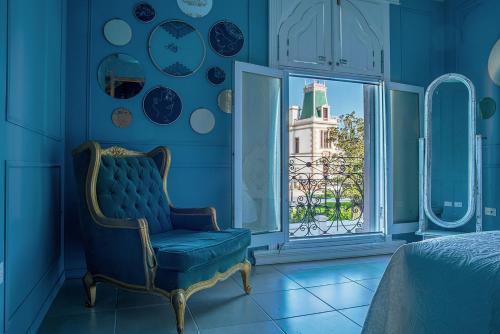 a blue room with a chair and a window at Doroteo Hotel Boutique in Chihuahua