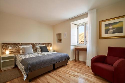 a bedroom with a bed and a red chair at Up Estalagem dos Padres in Albergaria-a-Velha