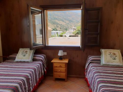 two twin beds in a room with a window at Hostal Pampaneira in Pampaneira