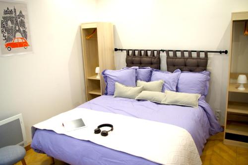 Le Poissonnière في باريس: غرفة نوم مع سرير بملاءات ووسائد أرجوانية