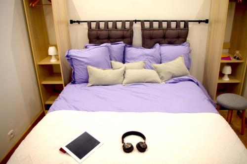 - un lit avec des oreillers violets et un livre dans l'établissement Le Poissonnière, à Paris