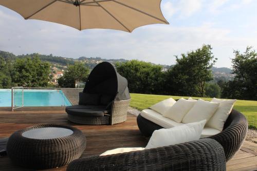 a patio with a couch and a chair and an umbrella at Casa de Coyra in Paredes de Coura