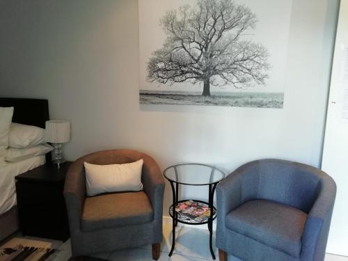 a bedroom with two chairs and a tree painting on the wall at The Palm in Cape Town