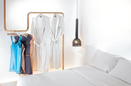 a bedroom with a white bed and a clothes rack at Santorini Soul Villas in Pirgos
