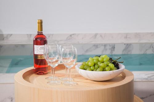 a bottle of wine and a bowl of grapes on a table at Santorini Soul Villas in Pirgos