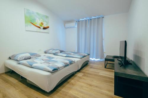 a bedroom with a bed and a flat screen tv at Apartmani Josip in Podstrana