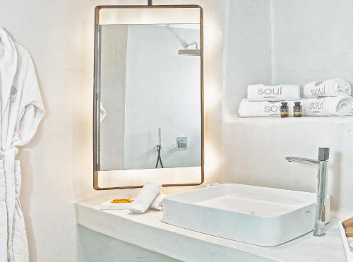 a white bathroom with a sink and a mirror at Santorini Soul Villas in Pirgos
